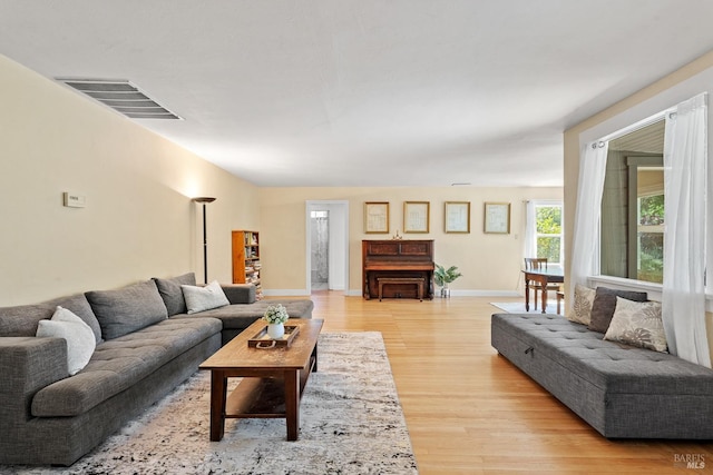 living room with visible vents, light wood-type flooring, and baseboards
