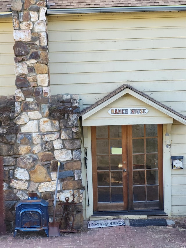 view of exterior entry with a shingled roof and stone siding