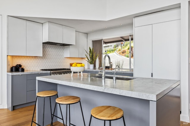 kitchen featuring a breakfast bar, tasteful backsplash, light wood finished floors, and a sink