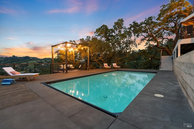 pool at dusk featuring an outdoor pool and a deck