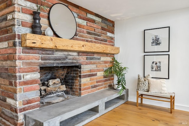 interior space featuring wood finished floors, baseboards, and a brick fireplace
