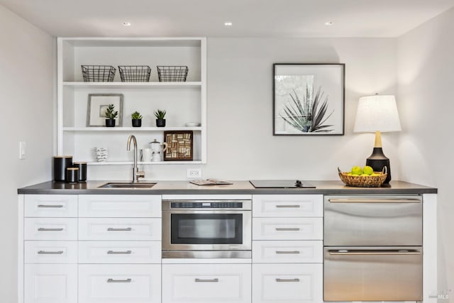 bar with black electric stovetop, a warming drawer, stainless steel oven, and a sink
