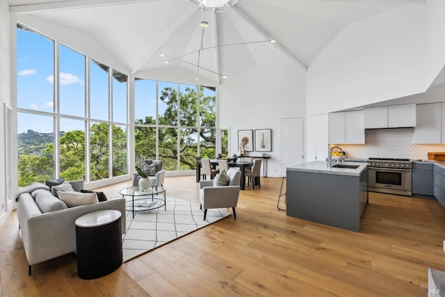 living room with light wood-style floors, a ceiling fan, and high vaulted ceiling