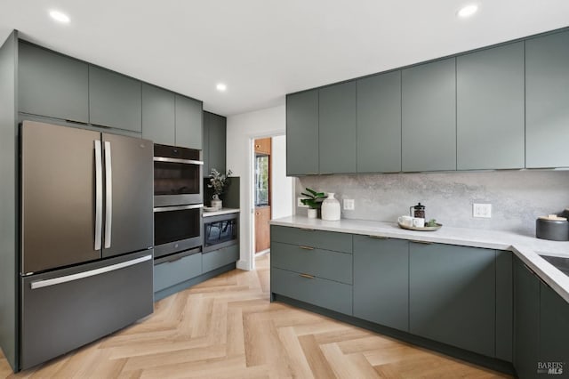 kitchen featuring light countertops, appliances with stainless steel finishes, modern cabinets, and tasteful backsplash