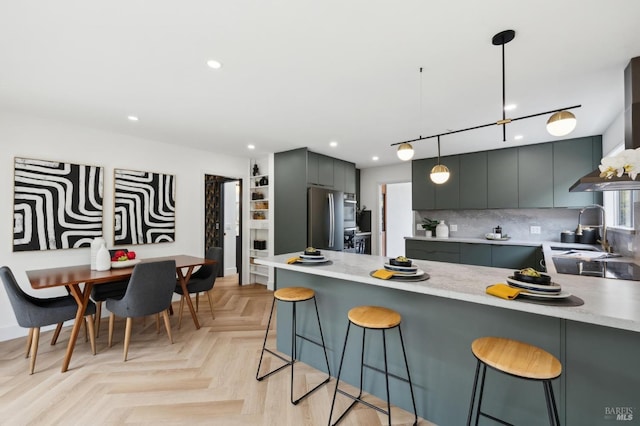 kitchen featuring freestanding refrigerator, a peninsula, a kitchen bar, a sink, and gray cabinetry