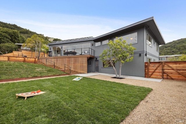 rear view of property featuring a yard, a patio, fence, and a gate