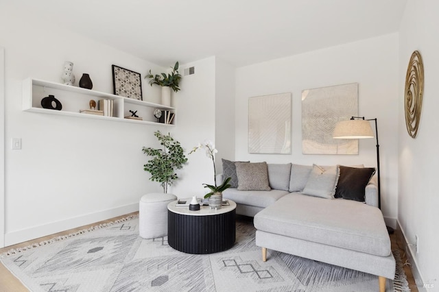 living room featuring visible vents, baseboards, and wood finished floors