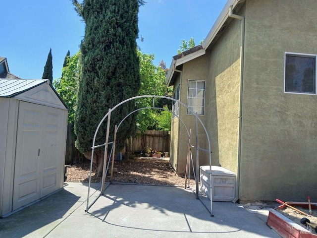 exterior space featuring fence, a storage unit, an outdoor structure, and a patio area