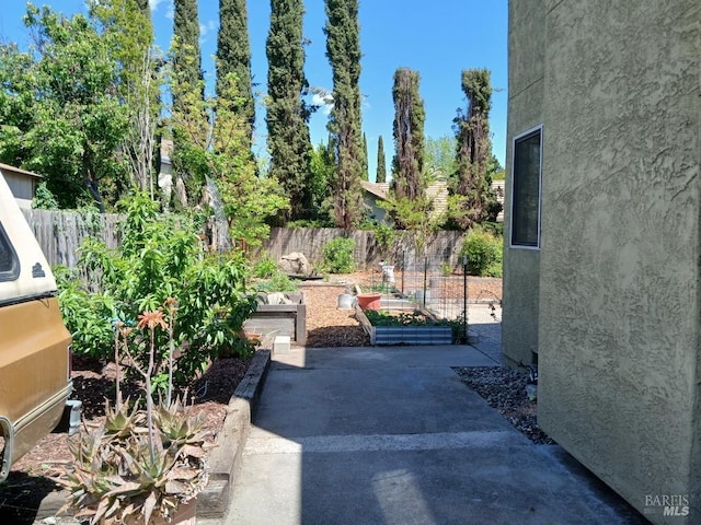 view of yard featuring fence, a garden, and a patio area