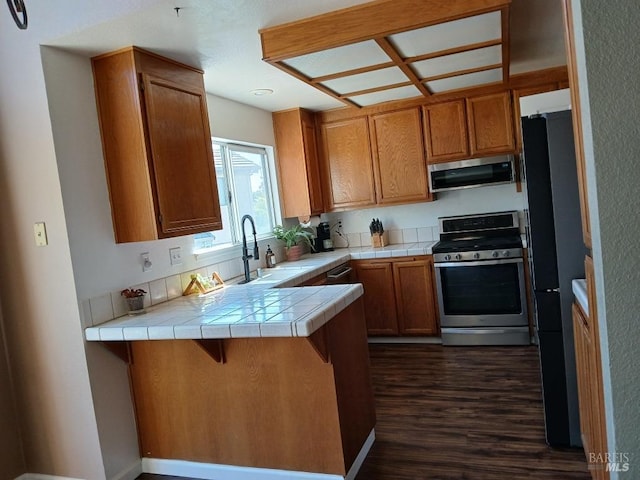 2998 Burl Ct, Fairfield, CA 94533 - kitchen with stainless steel appliances, a peninsula, dark wood finished floors, tile countertops, and brown cabinets