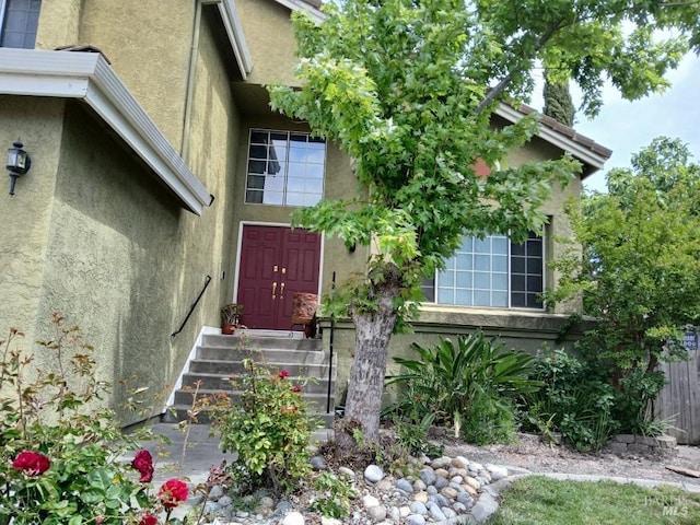 doorway to property featuring fence and stucco siding