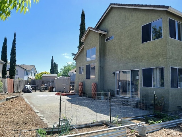 2998 Burl Ct, Fairfield, CA 94533 - back of property featuring a patio, a storage shed, a vegetable garden, stucco siding, and an outdoor structure