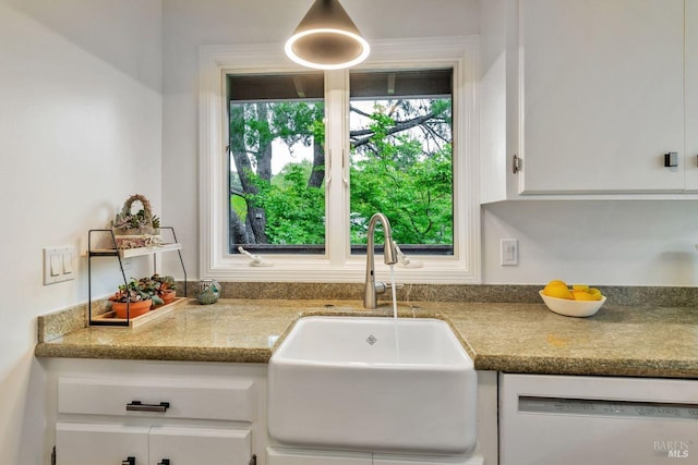 kitchen with plenty of natural light, a sink, dishwashing machine, and white cabinetry