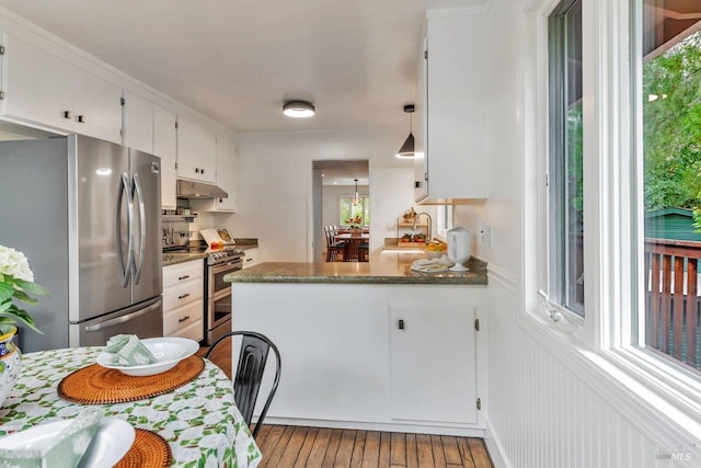 kitchen featuring wood-type flooring, a peninsula, plenty of natural light, white cabinetry, and appliances with stainless steel finishes