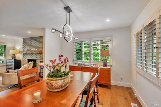 dining space featuring a notable chandelier, a brick fireplace, light wood-style flooring, recessed lighting, and baseboards