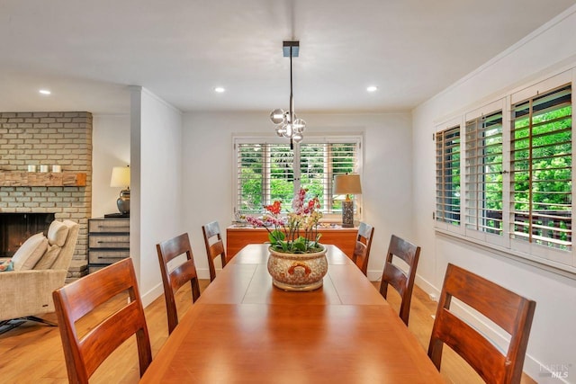dining space featuring a brick fireplace, recessed lighting, baseboards, and light wood-style flooring