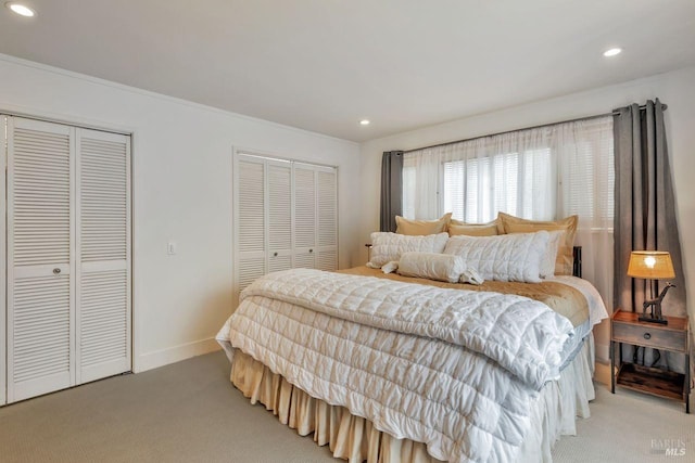 bedroom with recessed lighting, two closets, and light carpet