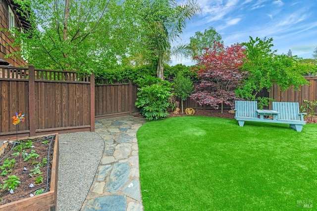 view of yard featuring a fenced backyard and a garden