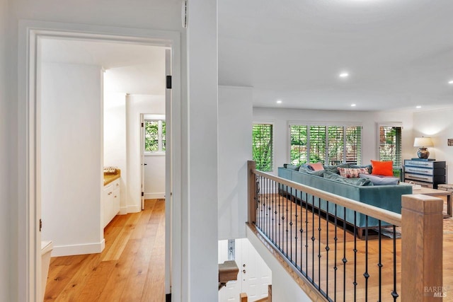 corridor with light wood-style floors, baseboards, recessed lighting, and an upstairs landing