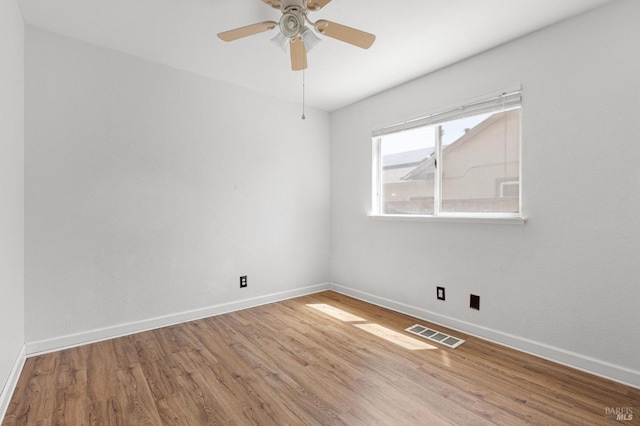 spare room with visible vents, ceiling fan, wood finished floors, and baseboards