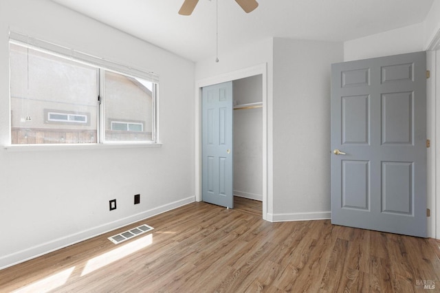 unfurnished bedroom with visible vents, a closet, baseboards, wood finished floors, and a ceiling fan