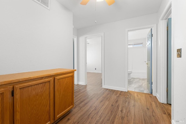 hallway featuring baseboards, visible vents, and wood finished floors