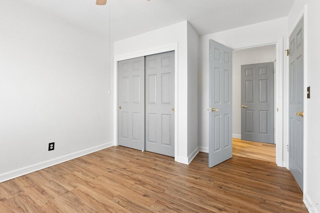 unfurnished bedroom featuring ceiling fan, light wood-type flooring, a closet, and baseboards