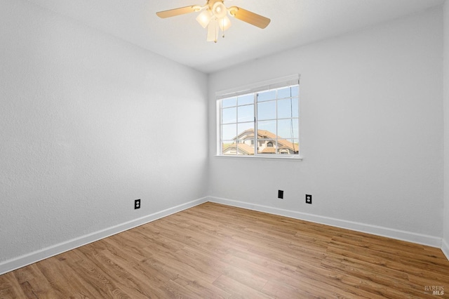 spare room featuring ceiling fan, baseboards, and light wood-style floors