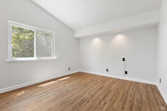 interior space featuring vaulted ceiling, wood finished floors, and baseboards