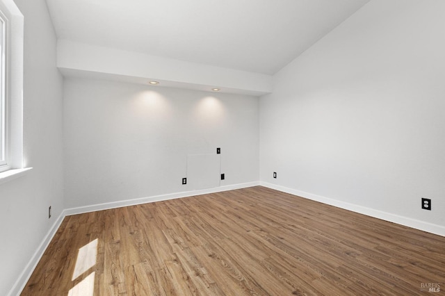 empty room with vaulted ceiling, wood finished floors, and baseboards