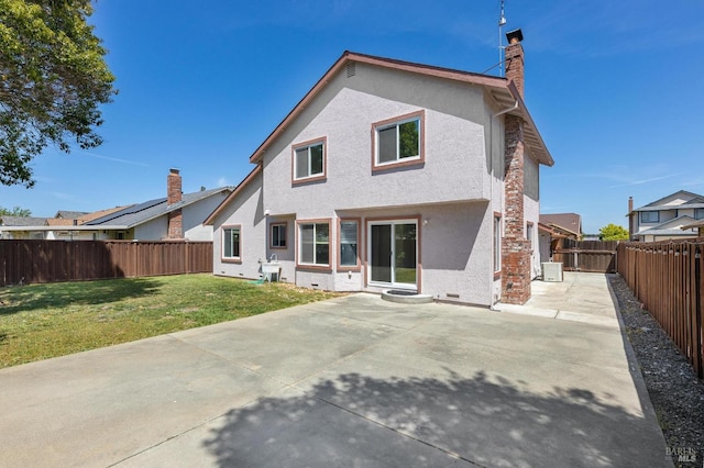 rear view of house featuring a patio, a chimney, stucco siding, a lawn, and a fenced backyard