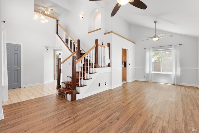 unfurnished living room featuring wood finished floors, a ceiling fan, high vaulted ceiling, and stairs