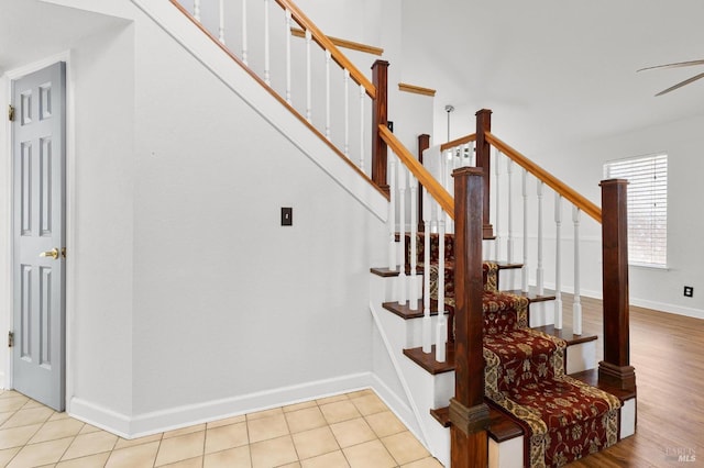 staircase with baseboards and ceiling fan