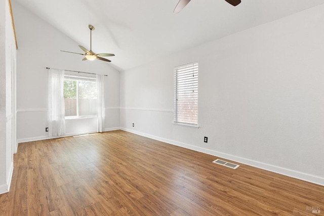 spare room featuring a ceiling fan, visible vents, wood finished floors, and lofted ceiling