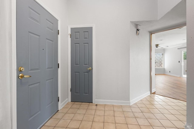 foyer entrance featuring light tile patterned floors, ceiling fan, and baseboards