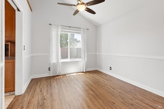 spare room featuring light wood-style floors, ceiling fan, visible vents, vaulted ceiling, and baseboards