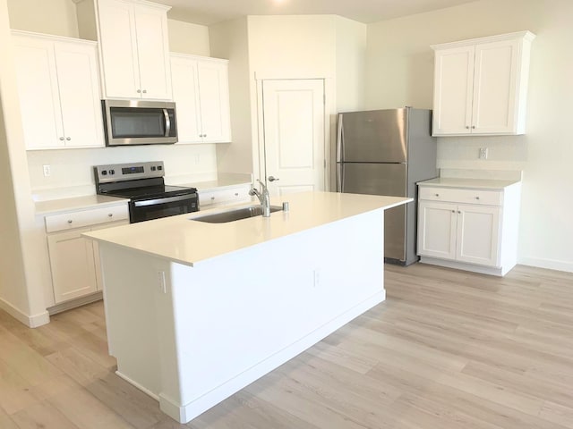 kitchen with a sink, white cabinets, stainless steel appliances, and light wood-style floors