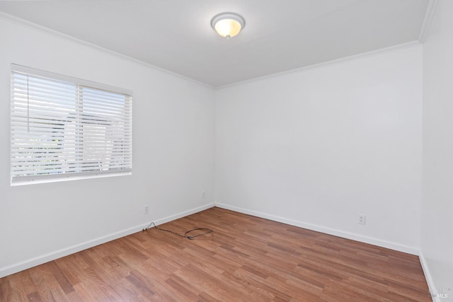 empty room featuring wood finished floors, crown molding, and baseboards
