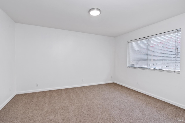 carpeted empty room featuring baseboards
