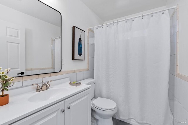 bathroom featuring vanity, toilet, and tile walls
