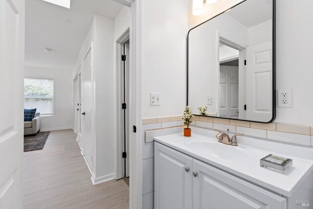 bathroom with baseboards, wood finished floors, and vanity