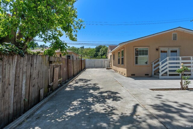 view of home's exterior with stucco siding, fence, a patio area, and crawl space