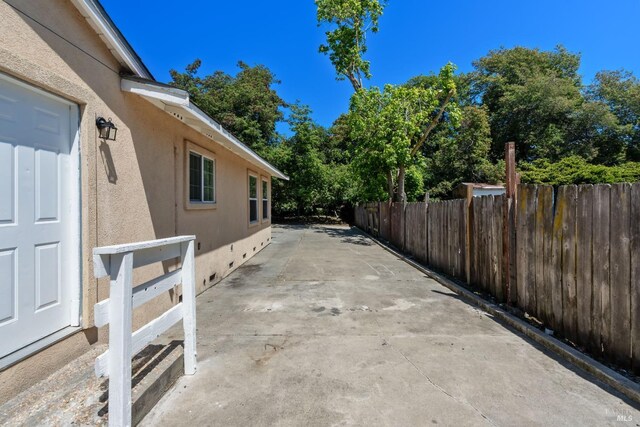view of side of property featuring fence, a patio, and stucco siding