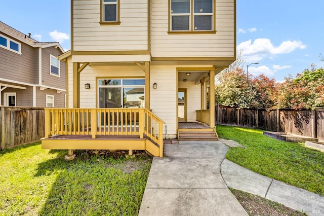 exterior space featuring a front yard, a wooden deck, and a fenced backyard