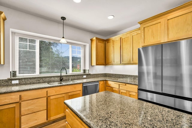 kitchen featuring decorative light fixtures, dark stone counters, stainless steel appliances, and a sink