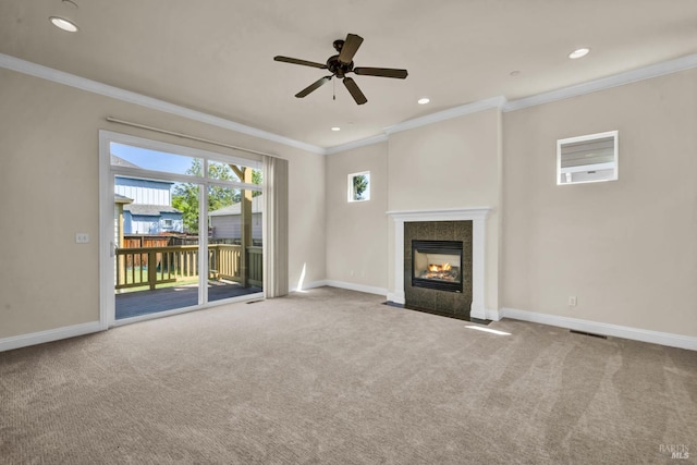 unfurnished living room with a tile fireplace, carpet floors, ceiling fan, baseboards, and crown molding