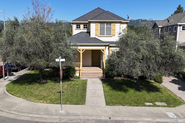 view of front of home with a porch, a front yard, and a shingled roof
