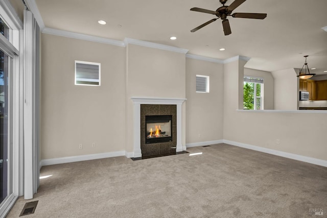 unfurnished living room with carpet, ornamental molding, ceiling fan, a fireplace, and visible vents