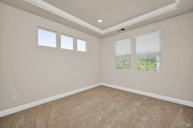empty room with carpet floors, ornamental molding, baseboards, visible vents, and a tray ceiling
