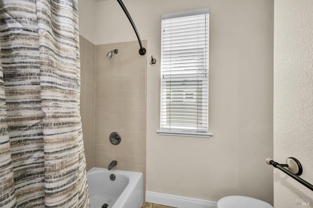bathroom with toilet, shower / bath combination with curtain, and baseboards